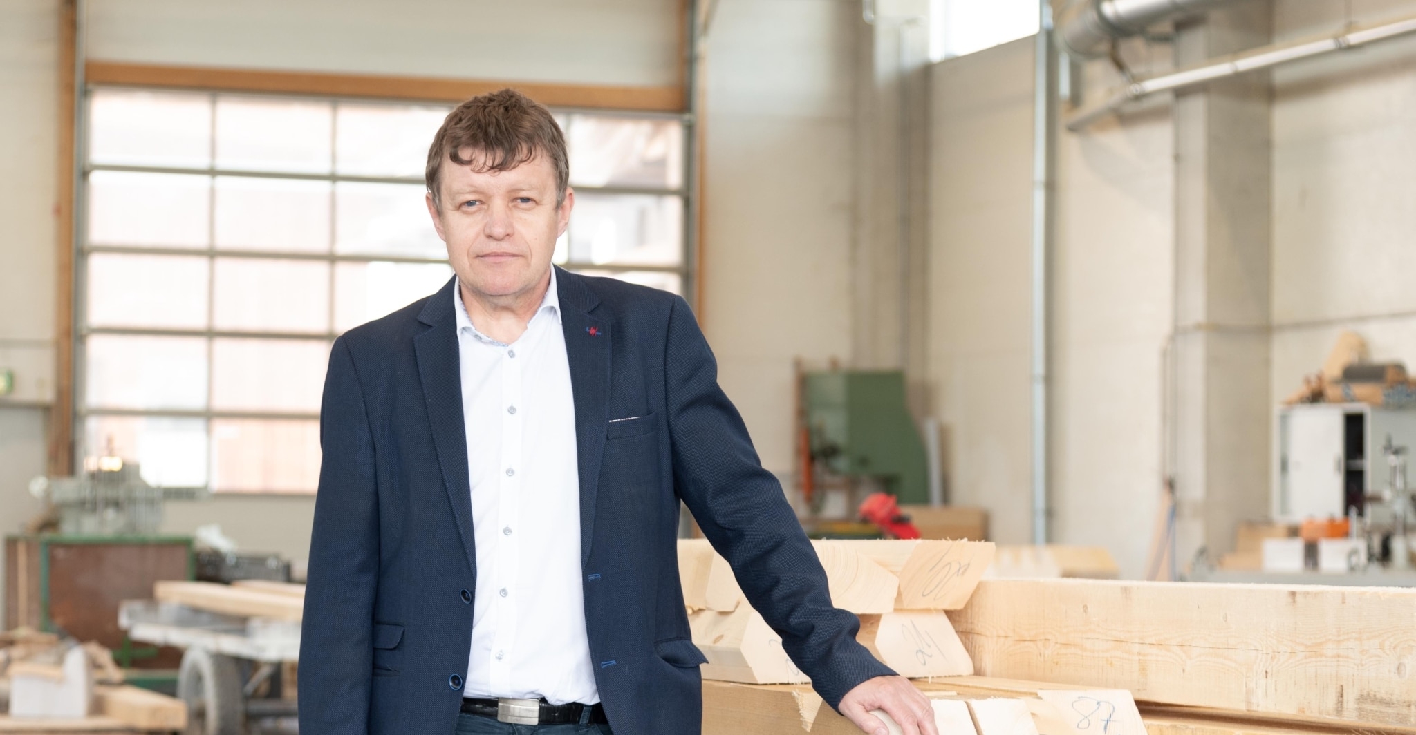 Prok. ZM Dominikus Jantscher Mann in einem Holzverarbeitungsbetrieb mit Holzstücken